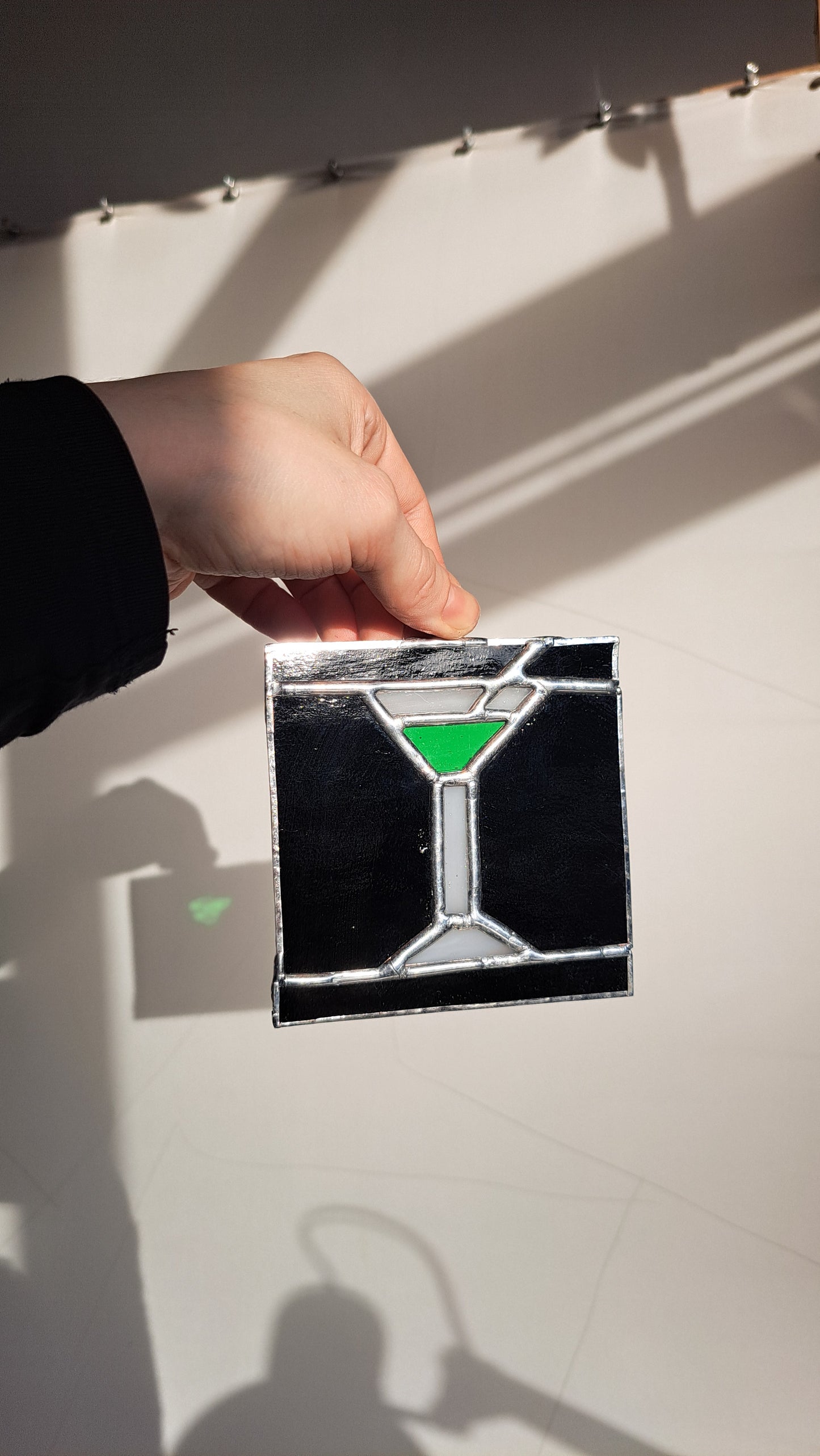 Hand holding a stained glass object of a martini cocktail