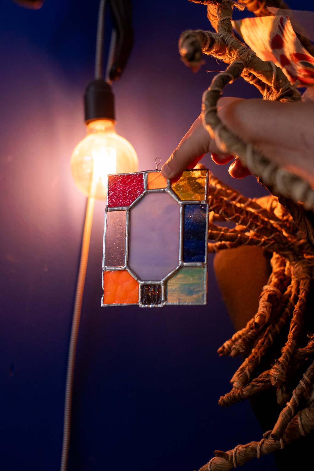 Decorative light bulb with a colorful stained glass design against a dark background.