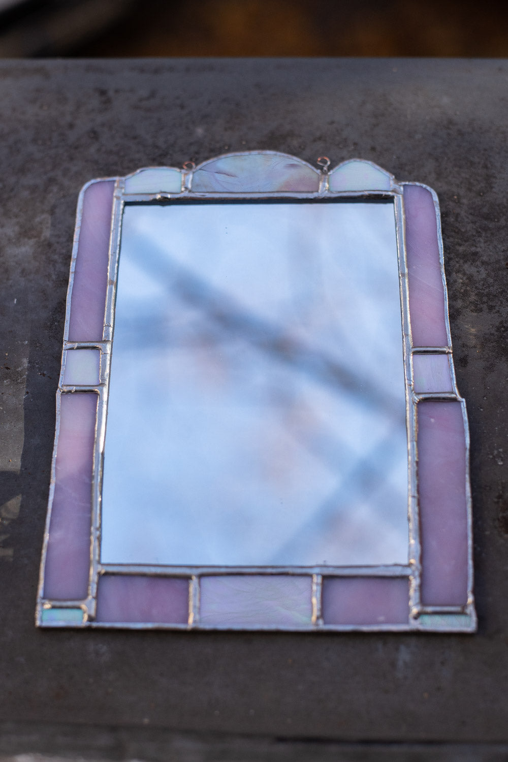 Stained glass mirror with pink and white colors on a dark surface