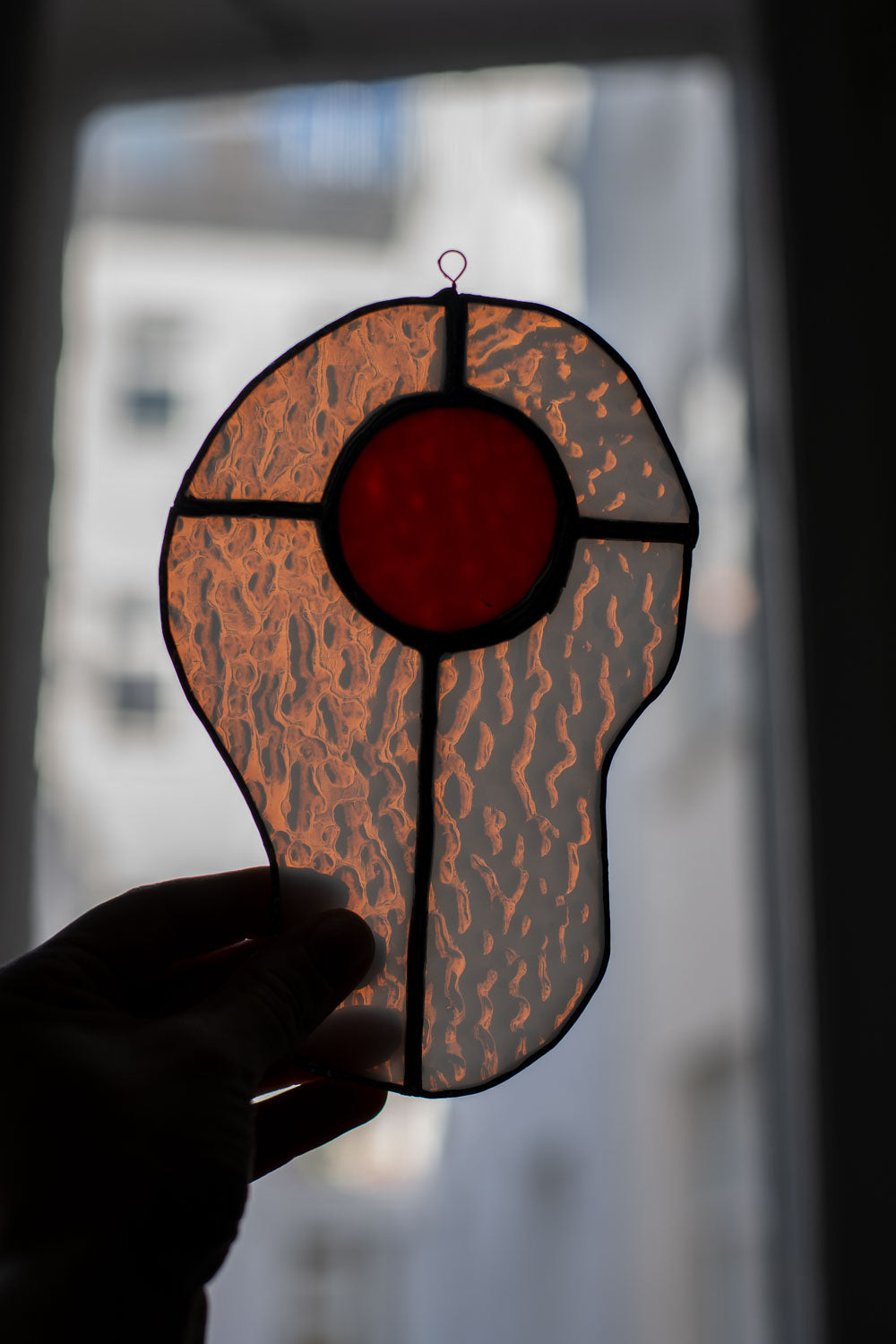 Egg-shaped stained glass artwork held by a hand with a blurred background