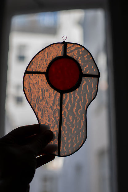 Egg-shaped stained glass artwork held by a hand with a blurred background