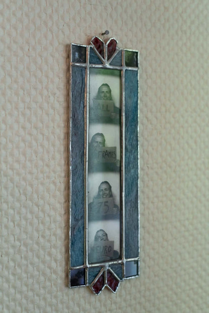 Decorative wall art with a blue frame and embedded photos on a textured beige wall.
