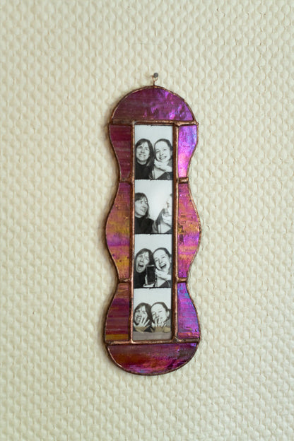 Decorative photo frame with a colorful, iridescent finish on a textured beige background.