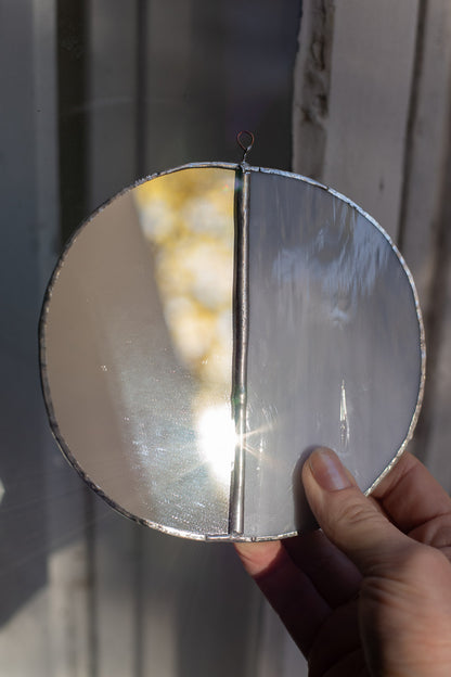 Hand holding a stained glass moon with reflective surface