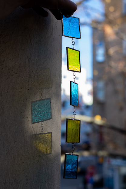 Colorful glass suncatcher hanging against a blurred urban background