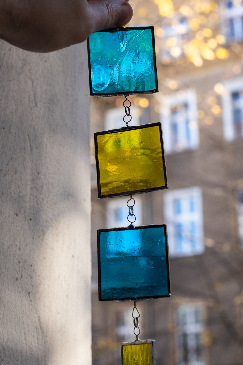 Colorful glass suncatcher held against a blurred indoor background
