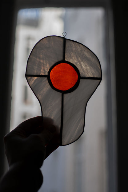 Egg-shaped stained glass piece held in front of a blurred background